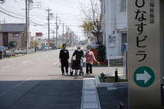 入居者と一緒に、外でシルバーカーで歩行訓練する職員